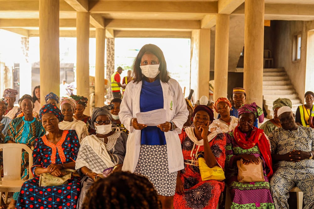 A doctor speaking to a seated group of older women during a community health talk